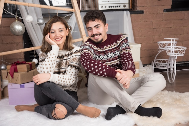 Free photo young adorable smiling couple sitting on the floor and posing.