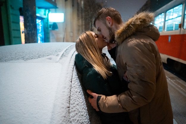 Free photo young adult couple kissing each other on snow covered street