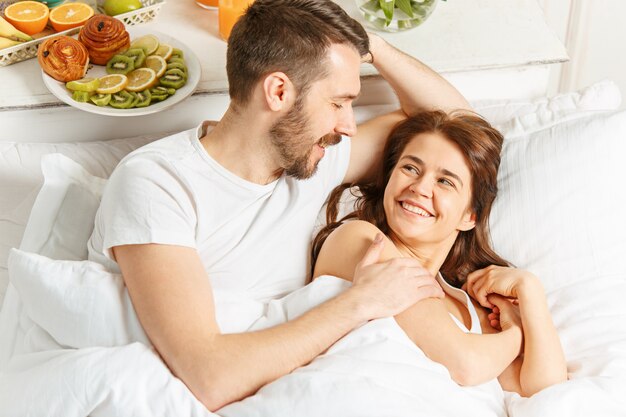 Young adult heterosexual couple lying on bed in bedroom