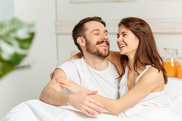 Young adult heterosexual couple lying on bed in bedroom