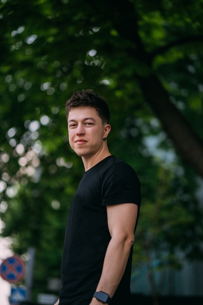 Young adult man in a black t-shirt and jeans walks on a city street