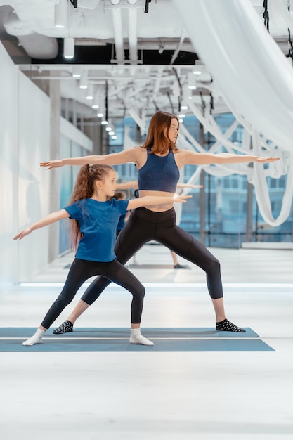 Young adult mom and little daughter together on aerobics