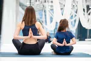 Free photo young adult mother and little daughter together practicing yoga