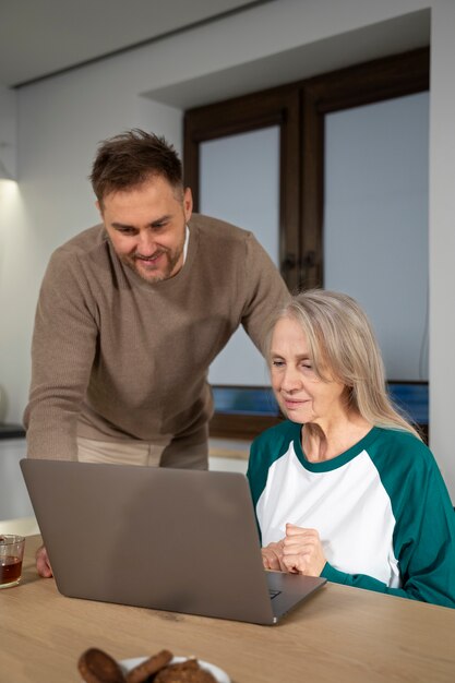 Young adult teaching elderly person about degital devicer