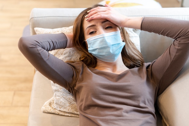 Free Photo young adult wearing a protection mask on couch