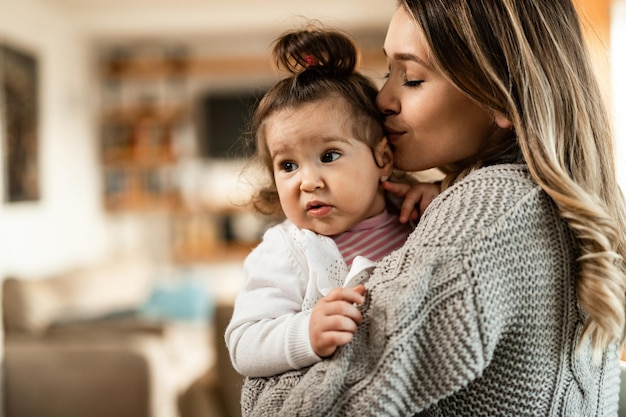 Free Photo young affectionate mother kissing her little girl while spending time with her at home