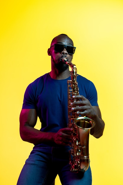 Young african-american jazz musician playing the saxophone on yellow