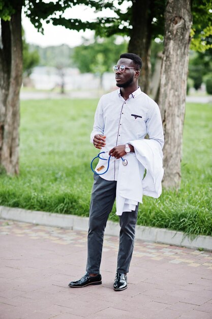 Young african american male doctor hold white coat on hand with a stethoscope posed outdoor