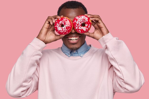 Young African American man holding tasty donuts