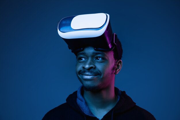 Young african-american man's playing in VR-glasses in neon light on gradient