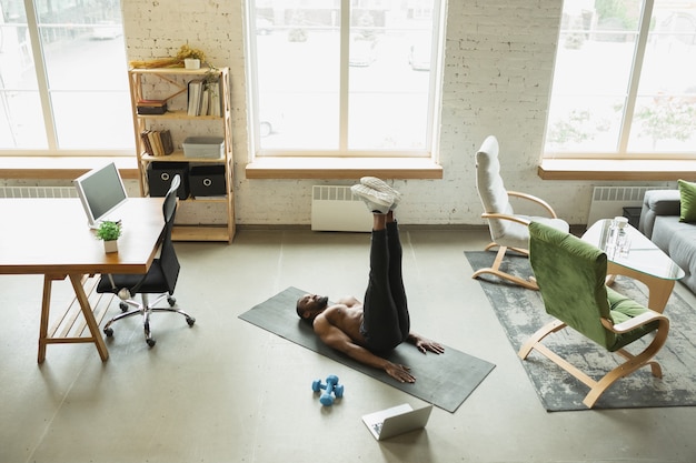 Free photo young african-american man training at home during quarantine