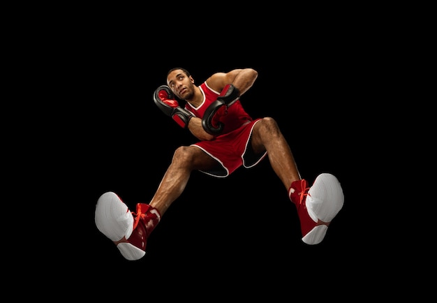 Free photo young african-american professional boxer in action, motion isolated on black wall, look from the bottom. concept of sport, movement, energy and dynamic, healthy lifestyle. training, practicing.