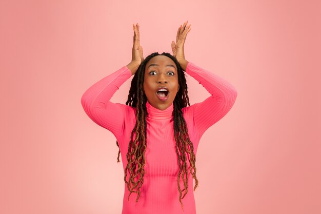 Young african-american woman's portrait isolated on pink background.