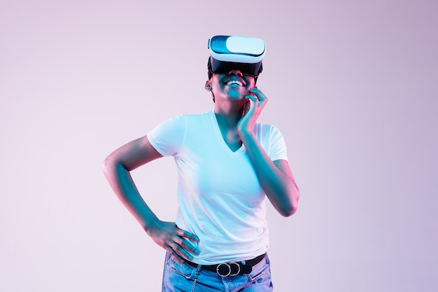 Young african-american woman's using VR-glasses in neon light