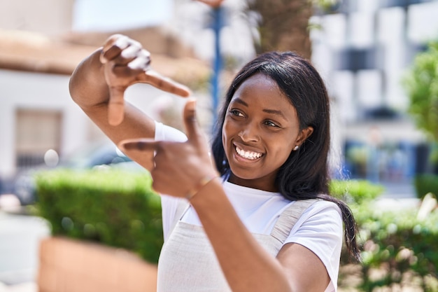 Young african american woman smiling confident doing photo gesture with hands at park