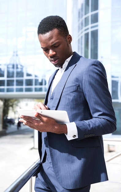 Young african businessman in blue suit using digital tablet at outdoors