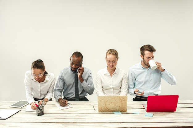 Young african and caucasian men and women sitting at office and working on laptops. The business, emotions, team, teamwork, workplace, leadership, meeting concept. different emotions of colleagues