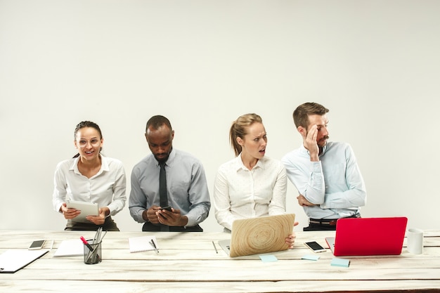 Free photo young african and caucasian men and women sitting at office and working on laptops. the business, emotions, team, teamwork, workplace, leadership, meeting concept. different emotions of colleagues