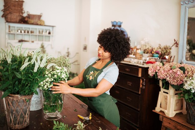 Young african female florist arranging flowers in shop