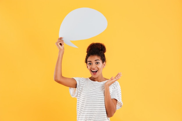 Young african happy thoughtful lady and holding blank speech bubble isolated over yellow