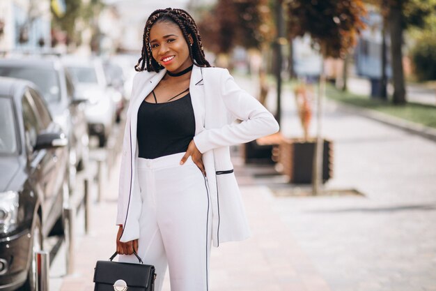 Young african woman dressed in white suit outside the street