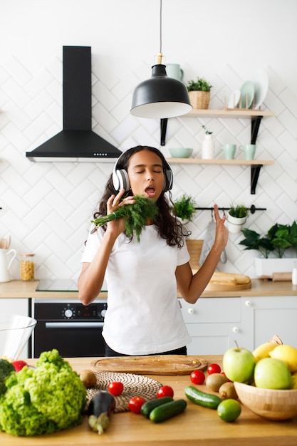 Young african woman emotional is listening to music via headphones and singing holds dill