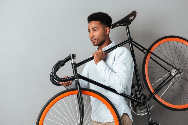 Young afro american man carrying bicycle