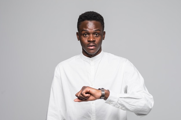 Young afro american man in shirt look at hand watch isolated on gray background