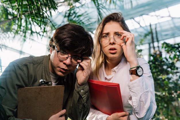 Young agricultural engineers working in big greenhouse