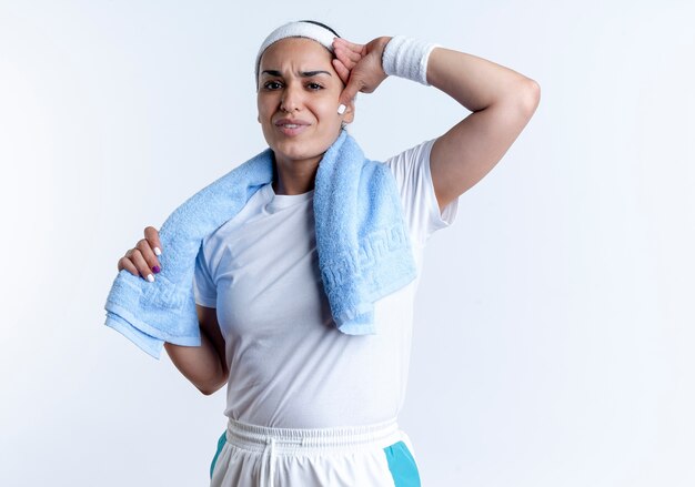 Young annoyed caucasian sporty woman wearing headband and wristbands with towel on neck puts hand on head isolated on white space with copy space