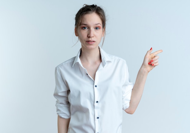 young anxious blonde russian girl points at side looking at camera