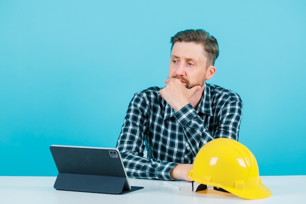 Free Photo young architect is thinking by holding hand on chin on blue background