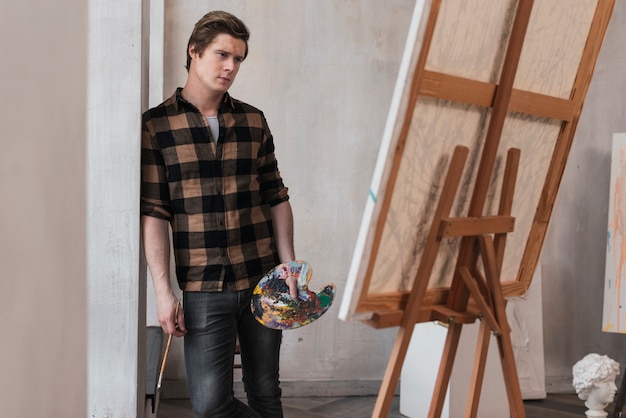 Free photo young artist looking at his picture in a studio