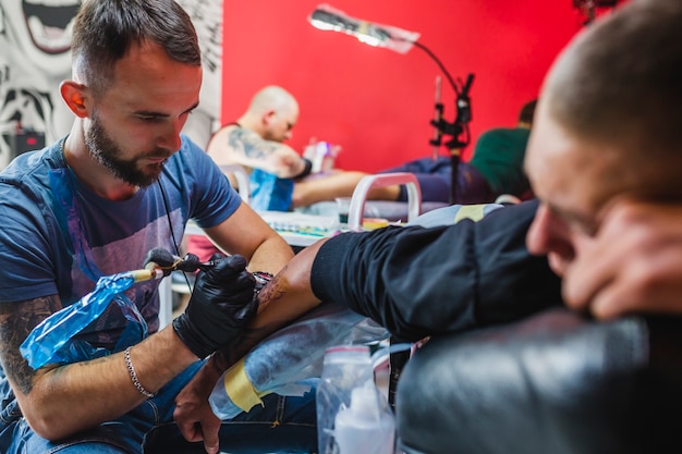 Young artist painting tattoo in studio