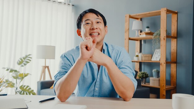 Young Asia businessman using computer laptop talk to colleagues about plan in video call meeting while working from home