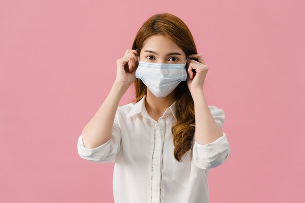 Young Asia girl wearing medical face mask with dressed in casual clothing and looking at camera isolated on pink background.