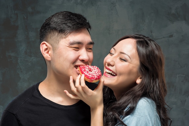 Free photo young asian couple enjoy eating of sweet colorful donut