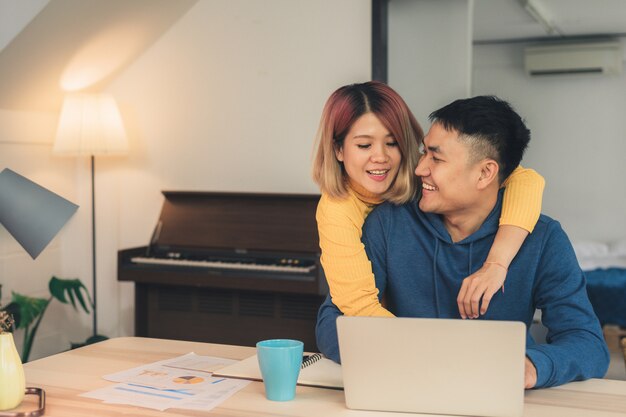 Young asian couple managing finances, reviewing their bank accounts using laptop computer