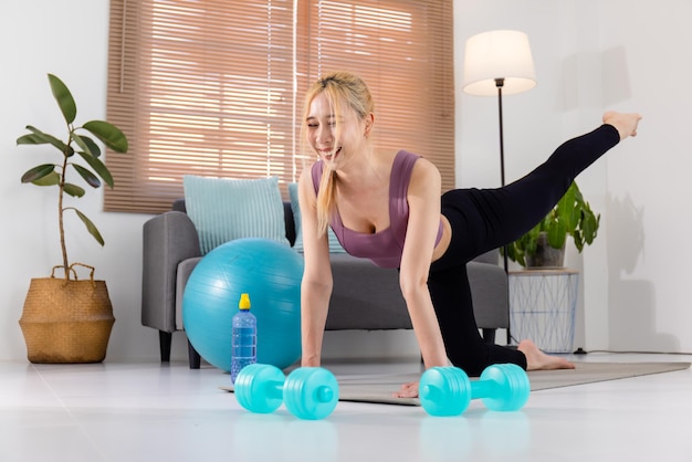 Free Photo young asian girl in a sports uniform performs an exercise on a sports mat at home