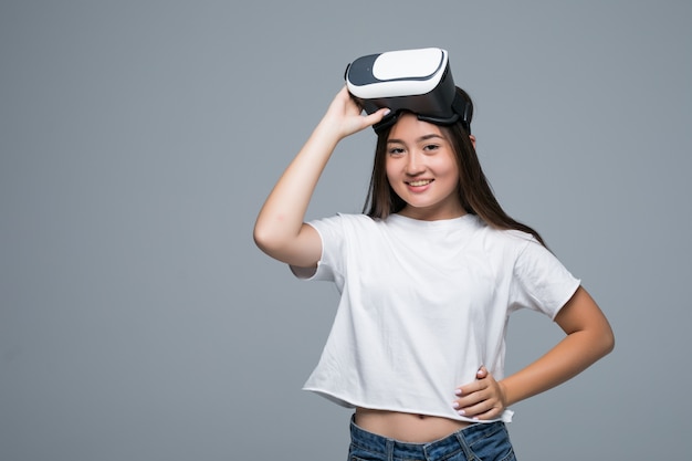 Young asian girl watching VR though and hand touch on air on gray background