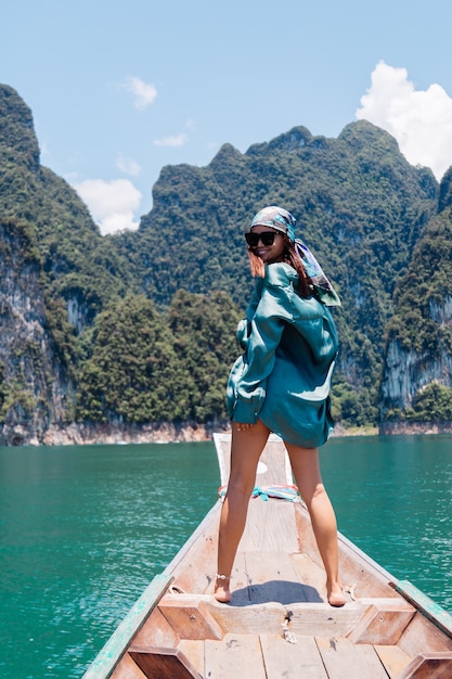 Free photo young asian happy woman blogger tourist in silk suit and scarf and sunglasses on vacation travel around thailand on asian boat, khao sok national park.