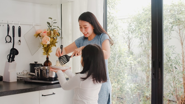 Free photo young asian japanese mom and daughter cooking at home. lifestyle women happy making pasta and spaghetti together for breakfast meal in modern kitchen at house in the morning .