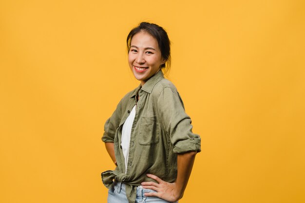 Young Asian lady with positive expression, smile broadly, dressed in casual clothing  over yellow wall. Happy adorable glad woman rejoices success. Facial expression concept.