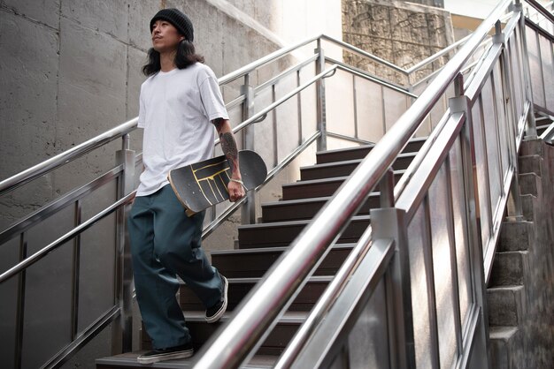 Young asian man holding his skateboard