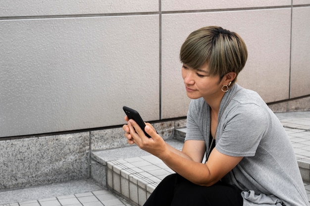 Young asian woman checking her phone outdoors