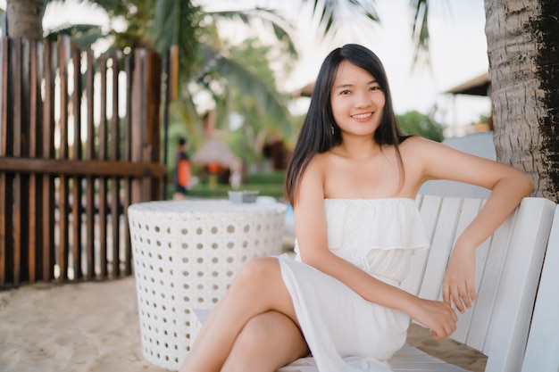 Free photo young asian woman sitting on bench relax on beach, beautiful female happy relax near sea.