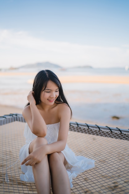 Young Asian woman sitting on hammock relax on beach, Beautiful female happy relax near sea.