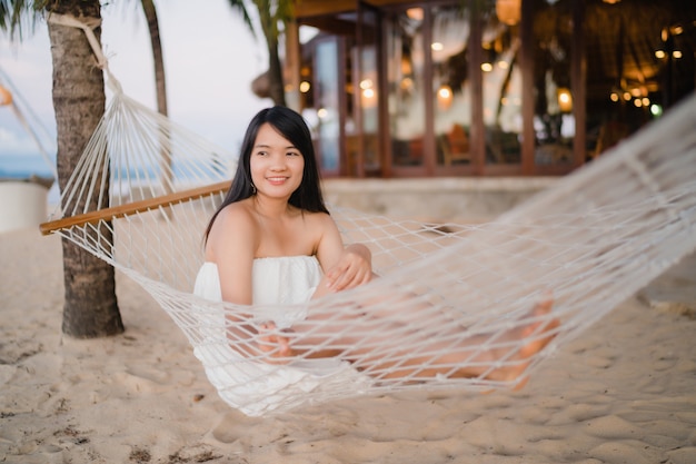 Young Asian woman sitting on hammock relax on beach, Beautiful female happy relax near sea.