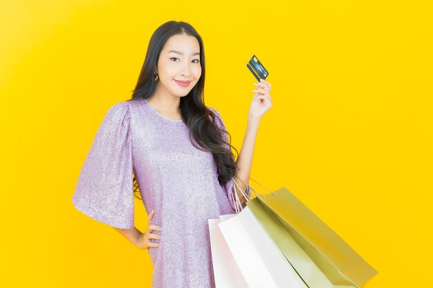 young asian woman smiling with shopping bag on yellow