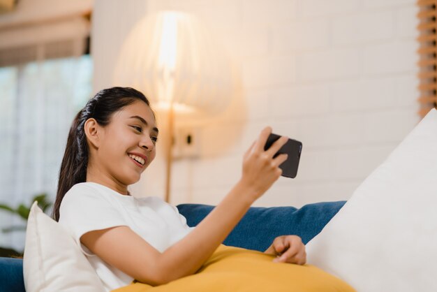 Young Asian woman using smartphone checking social media feeling happy smiling 